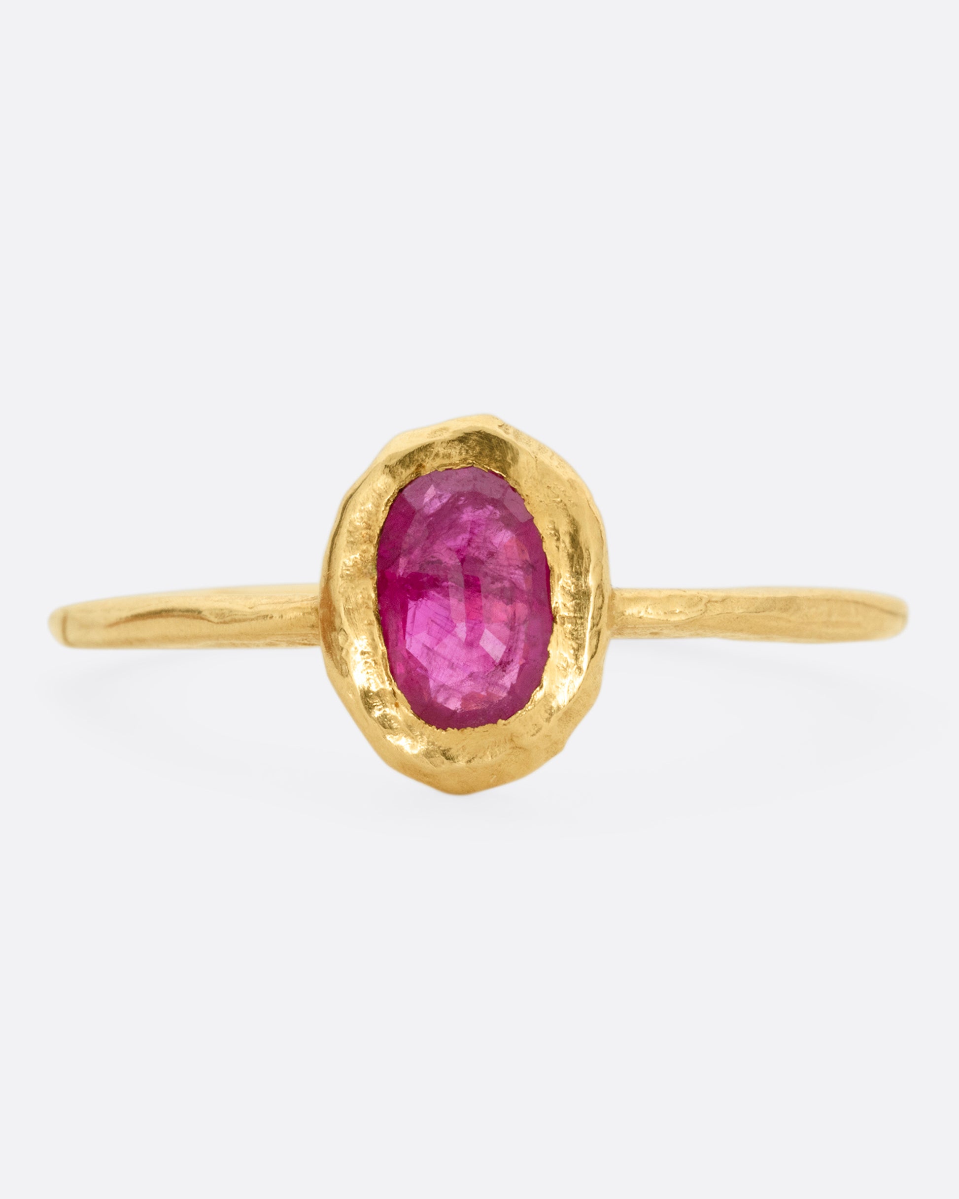 A yellow gold ring with a bezel set ruby, shown from the front.