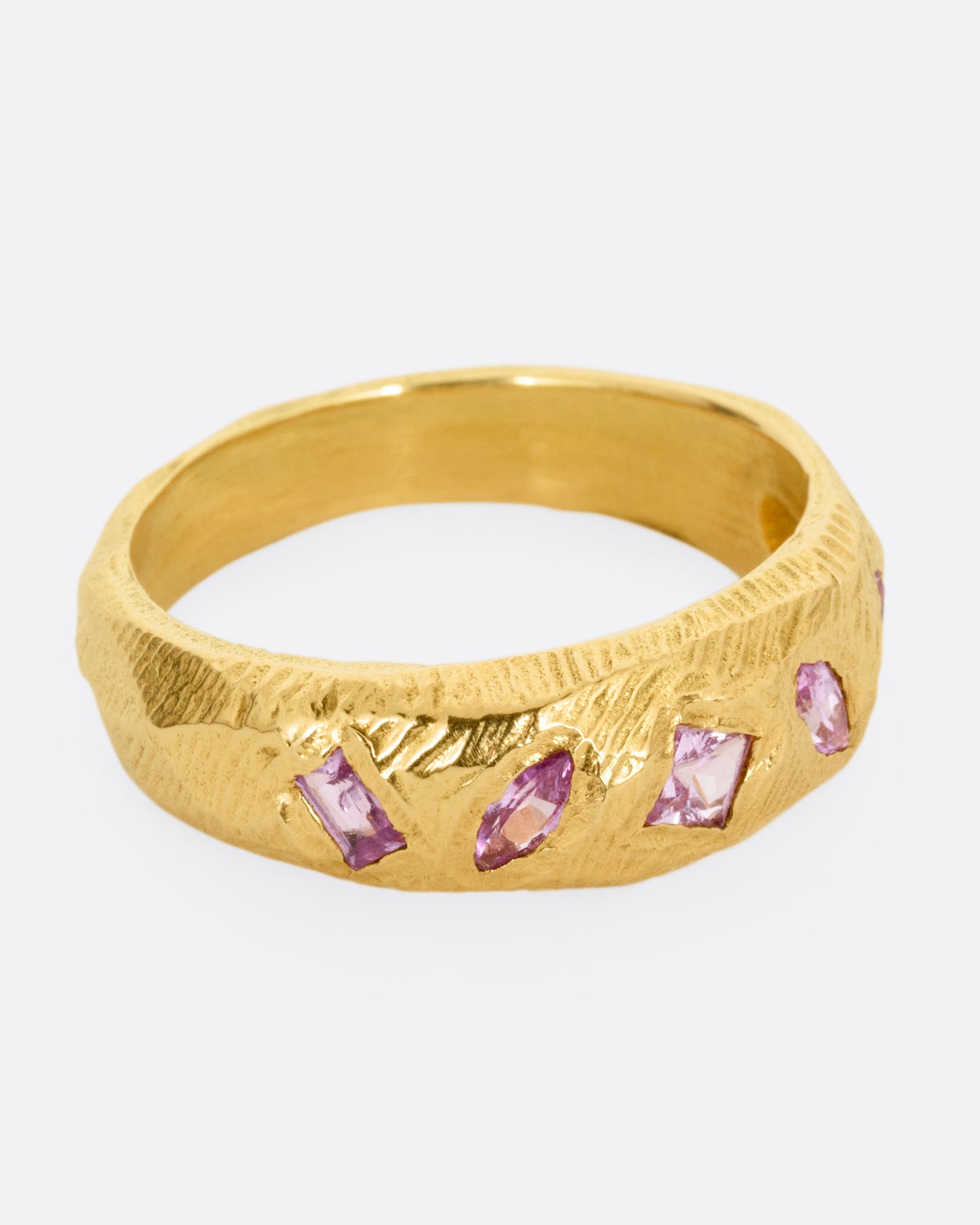 A yellow gold band with five pink sapphires, shown from the side.