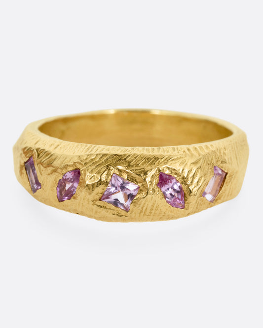 A yellow gold band with five pink sapphires, shown from the front.