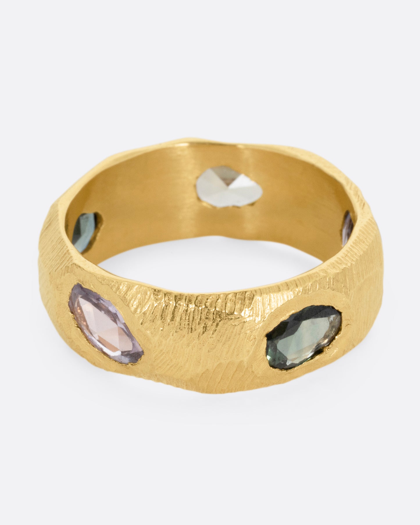 A yellow gold ring with rose cut sapphires in cool blues and greens, shown from the top at an angle.