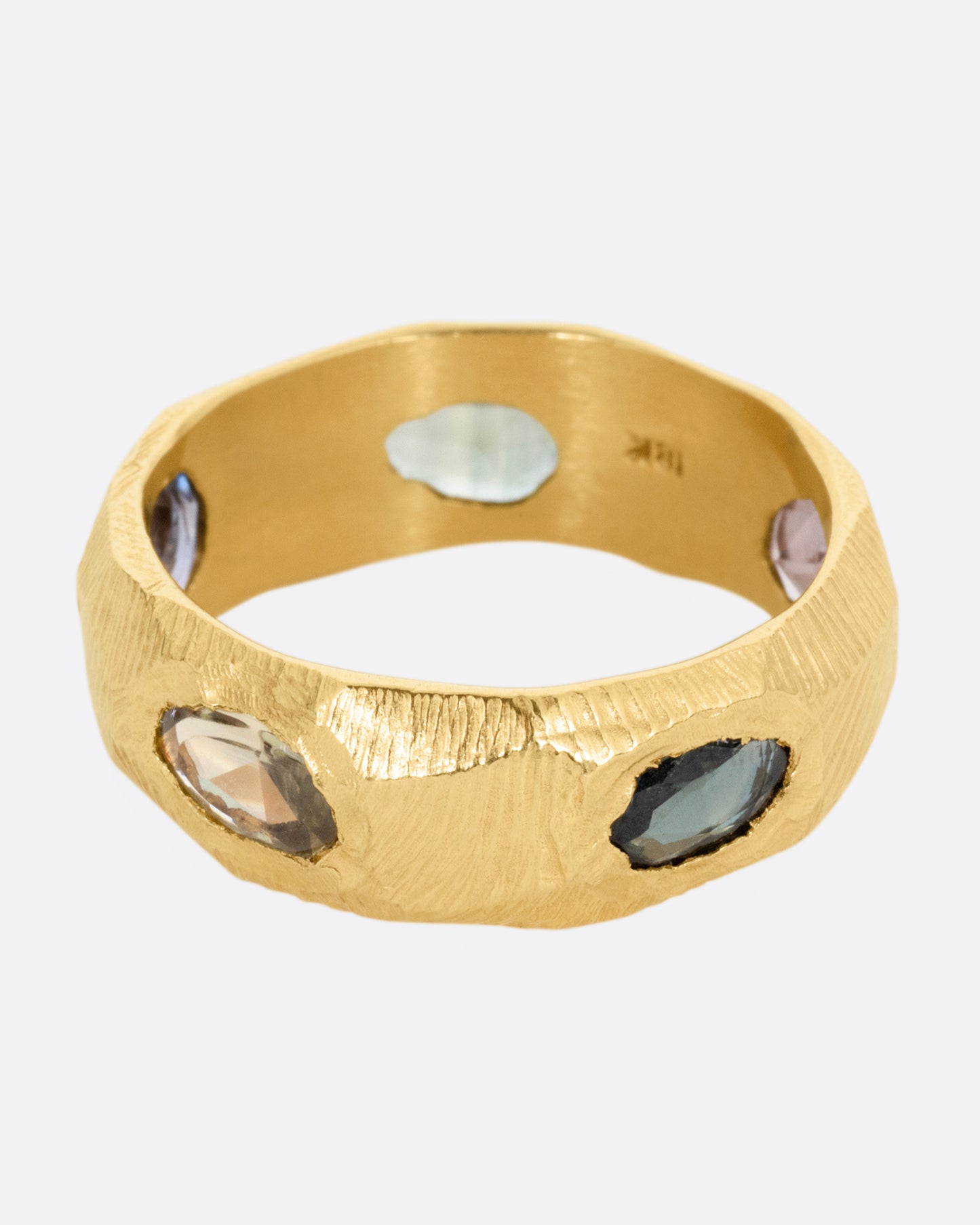 A yellow gold ring with rose cut sapphires in cool blues and greens, shown from the front.