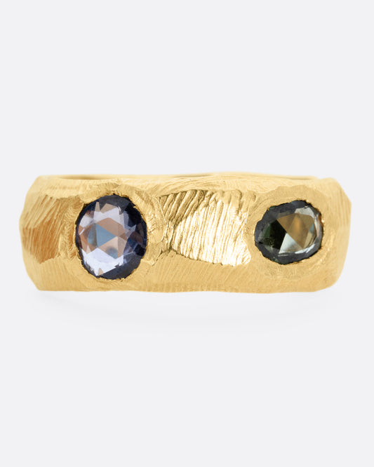 A yellow gold ring with rose cut sapphires in cool blues and greens, shown from the front.