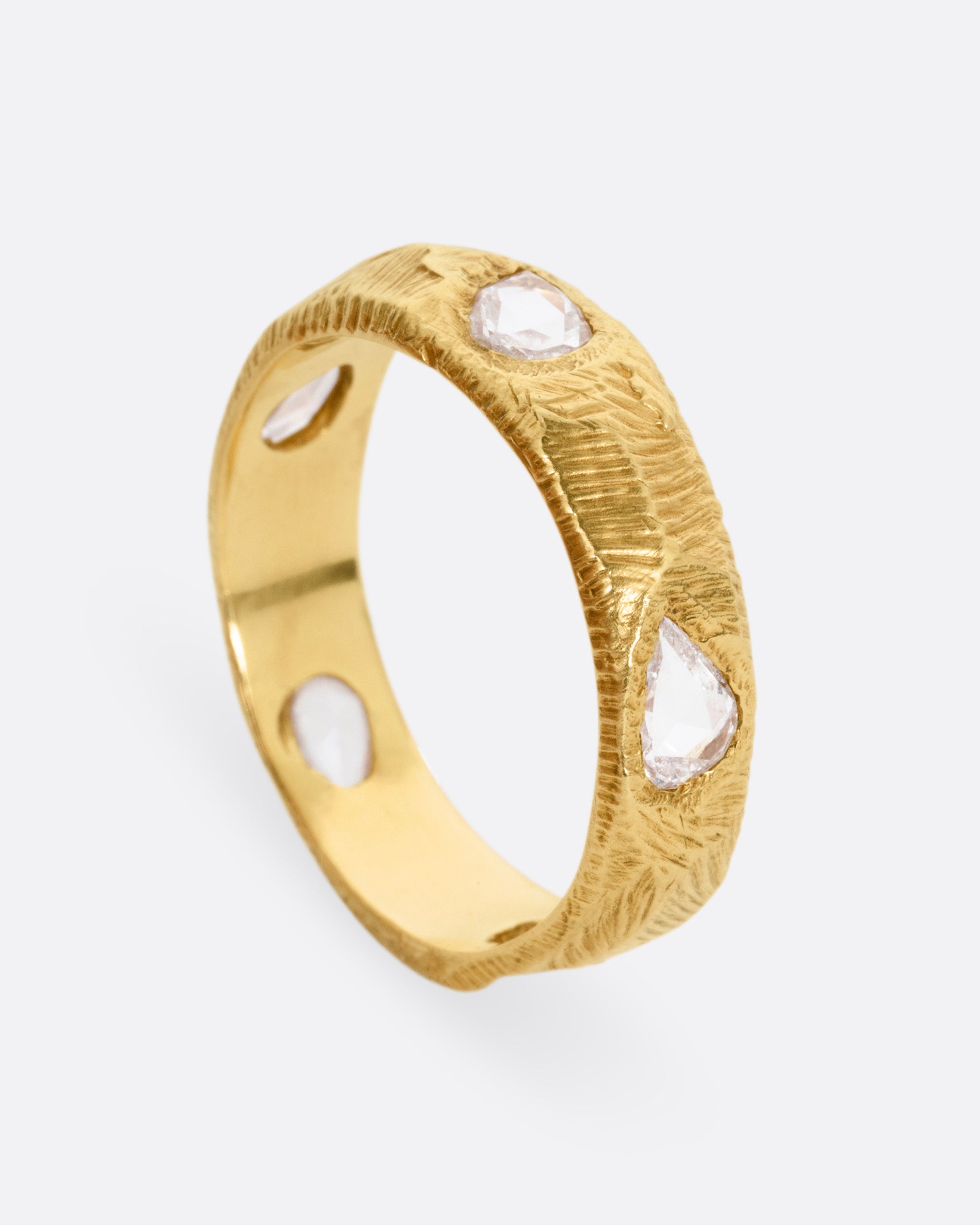 A yellow gold ring with five freeform rose cut diamonds, shown standing up from the side.