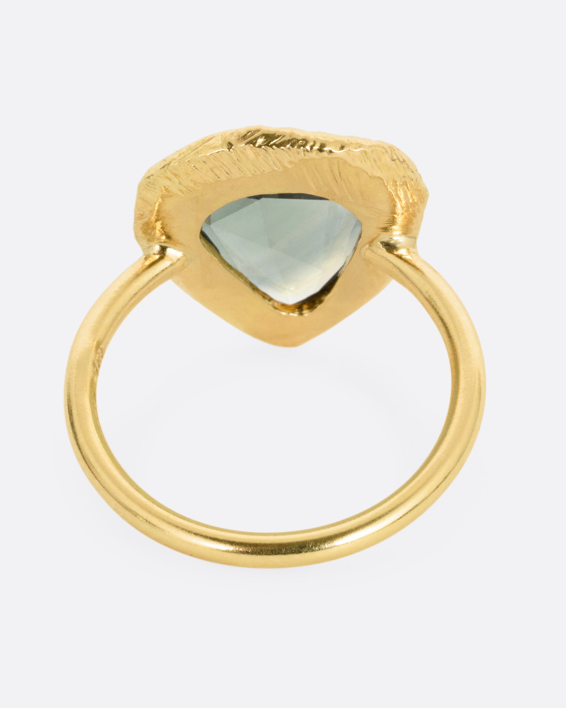 A yellow gold ring with a large sage green sapphire, shown from the back.