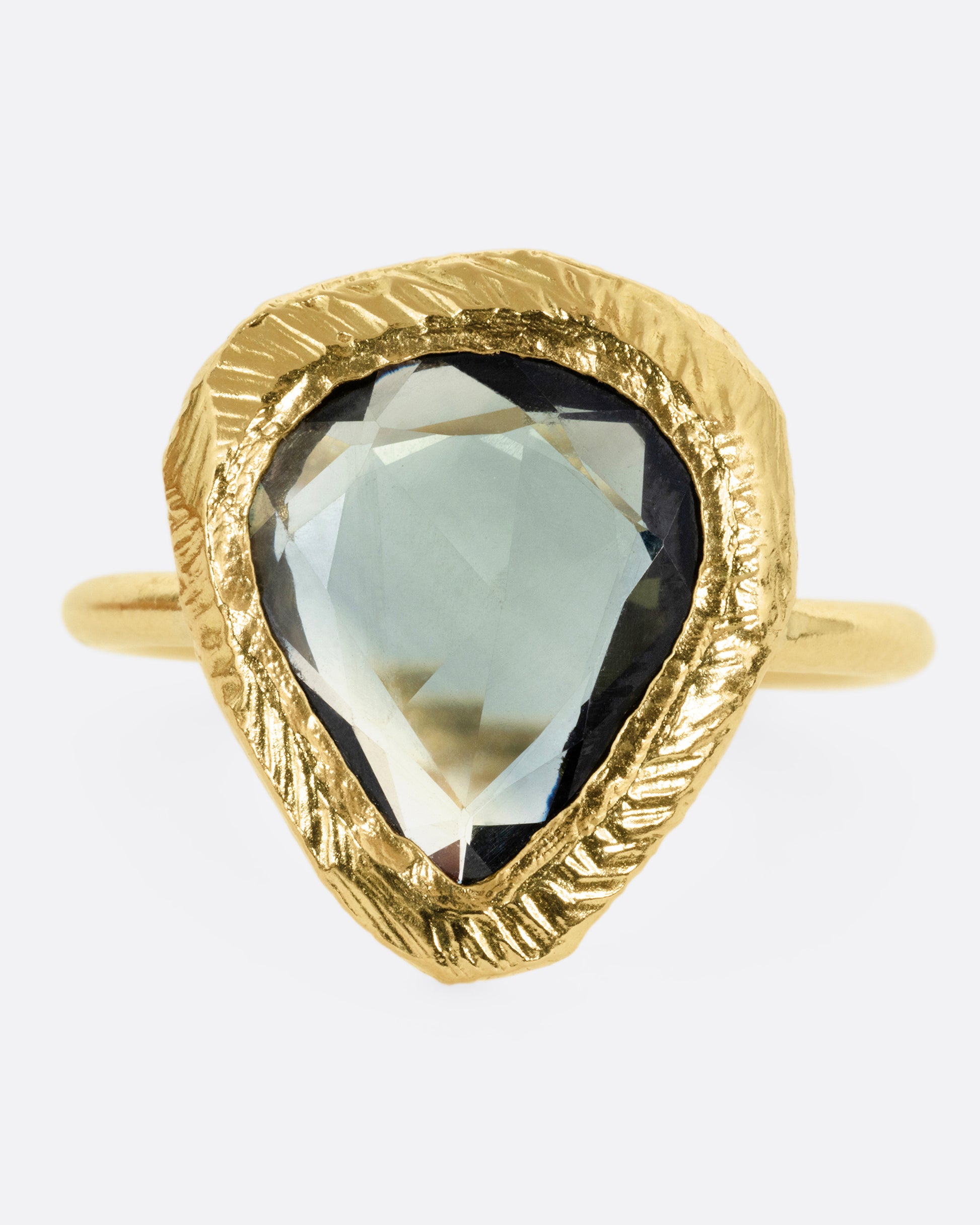 A yellow gold ring with a large sage green sapphire, shown from the front.