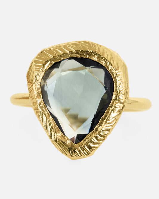 A yellow gold ring with a large sage green sapphire, shown from the front.
