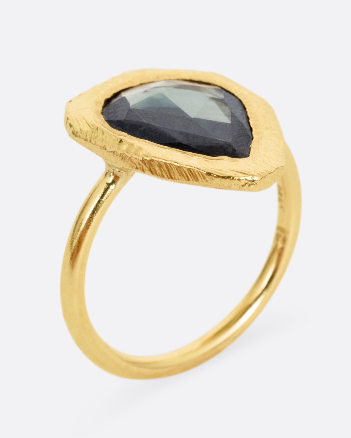 A yellow gold ring with a large sage green sapphire, shown from the side standing up.