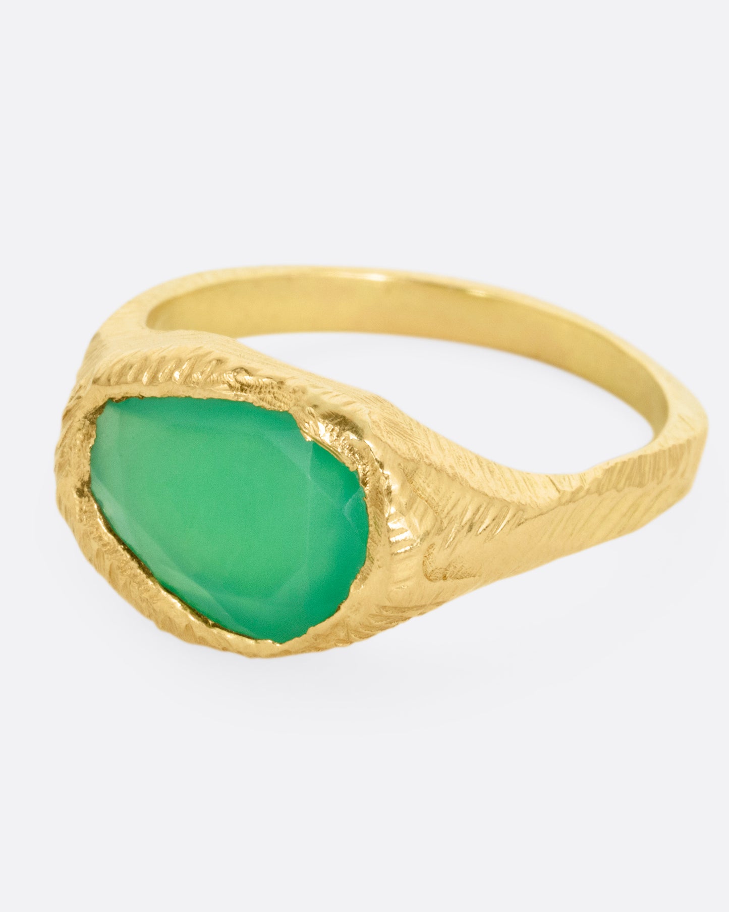 A yellow gold ring with a large chrysoprase, shown from the front at an angle.