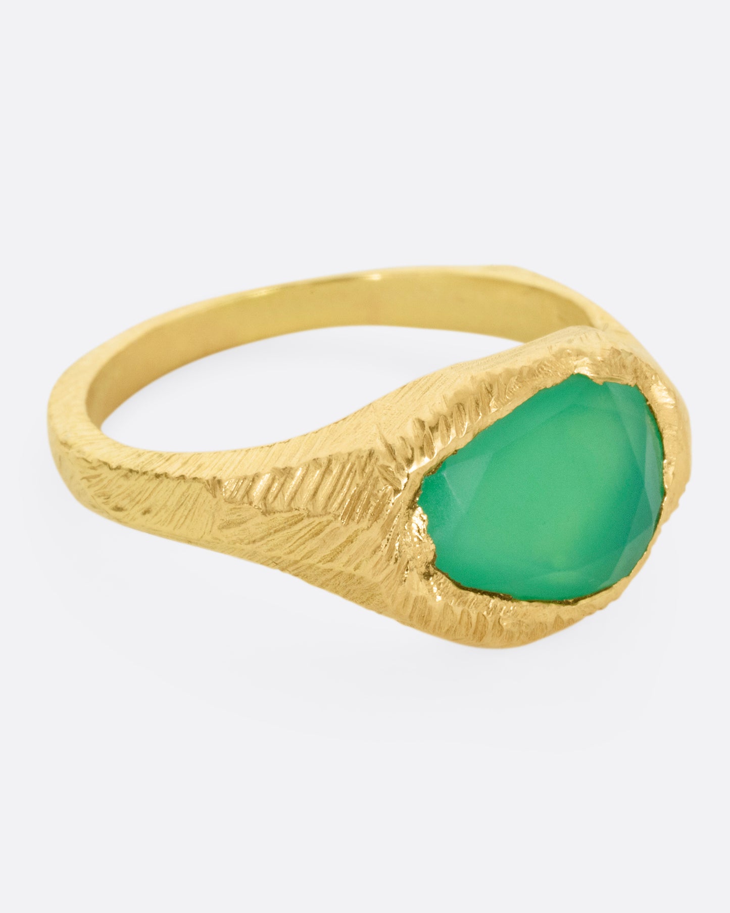 A yellow gold ring with a large chrysoprase, shown from the side.