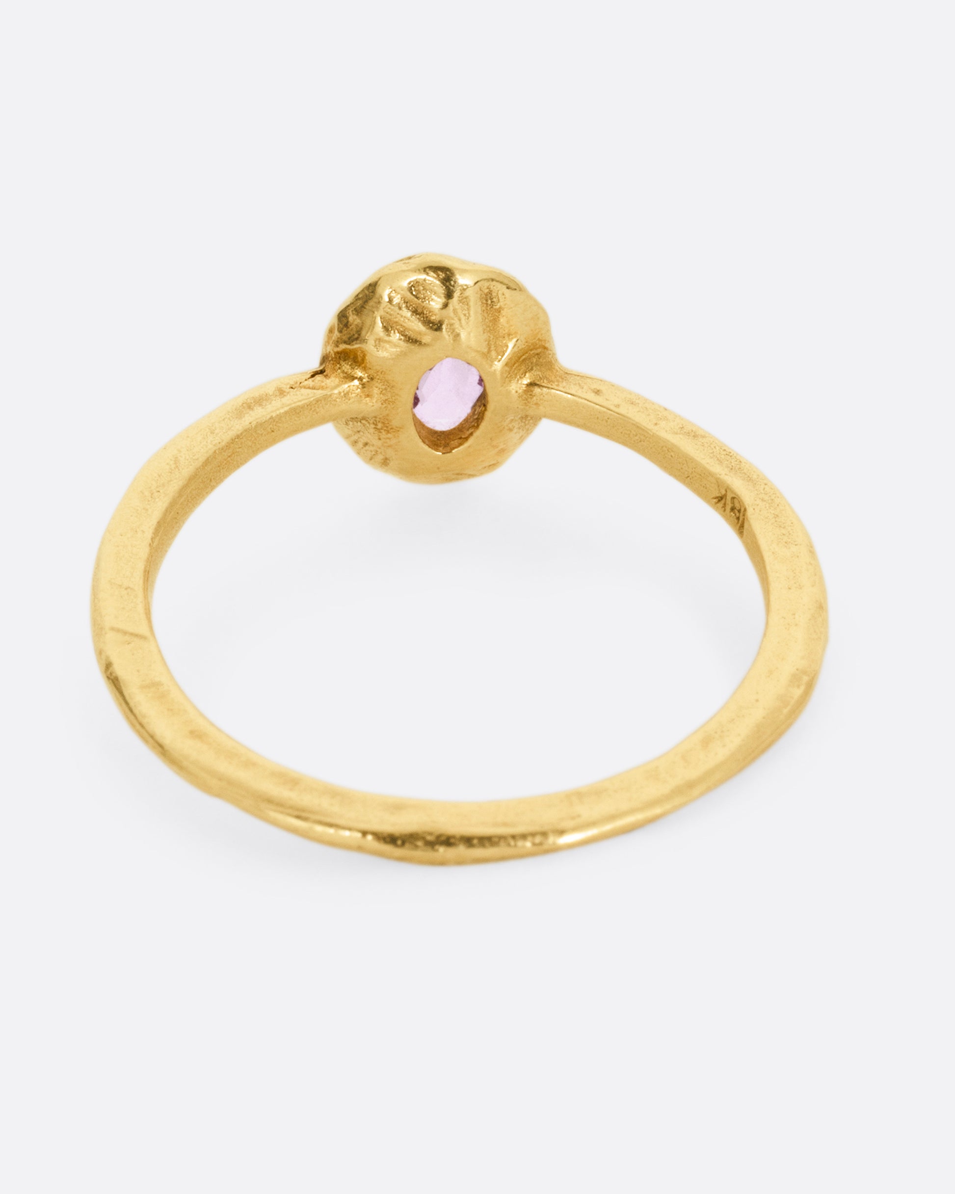 A yellow gold ring with a  pale pink sapphire in a hand carved bezel. Shown from the back.