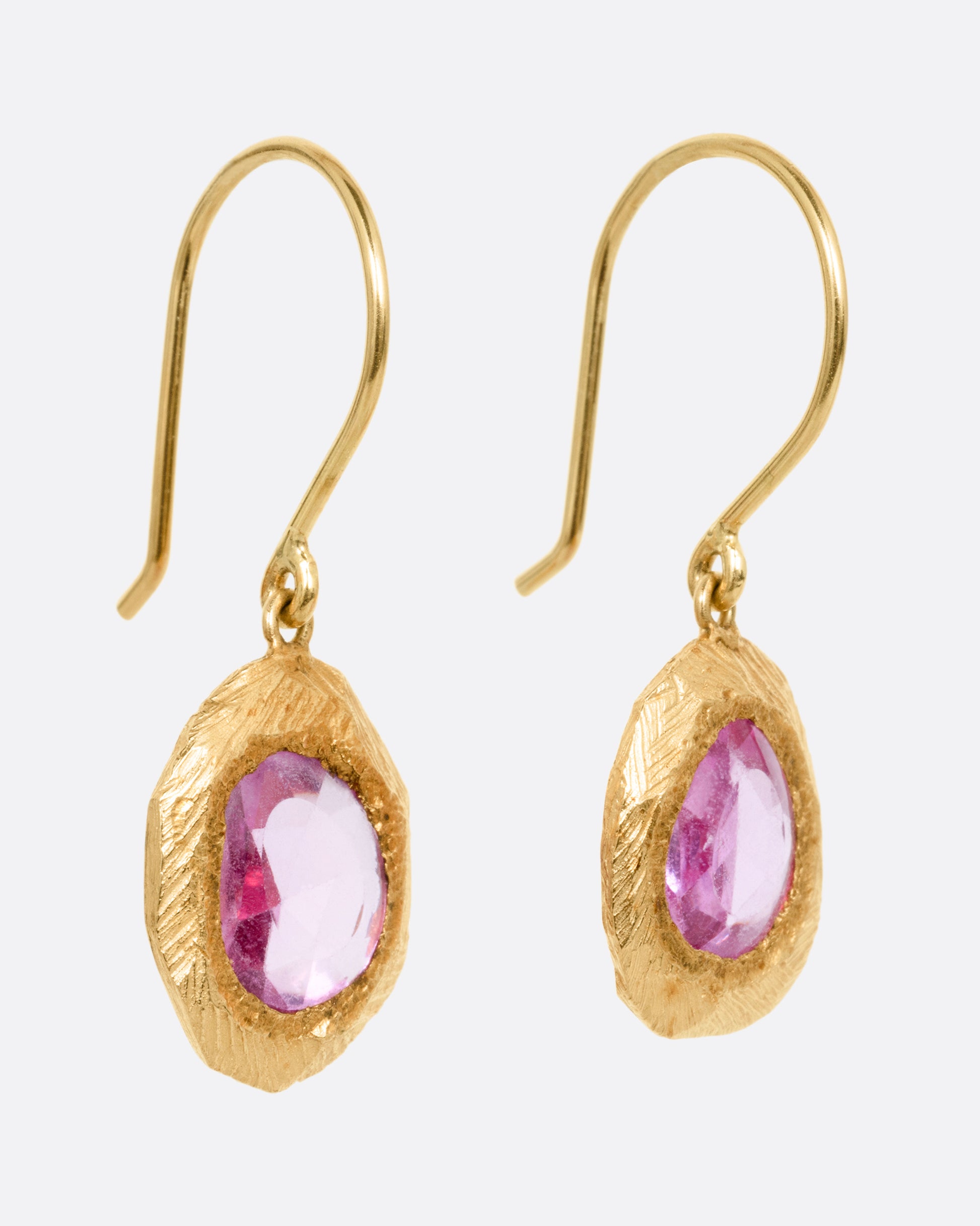 A pair of yellow gold drop earring with rose cut pink sapphires. Shown from the side.