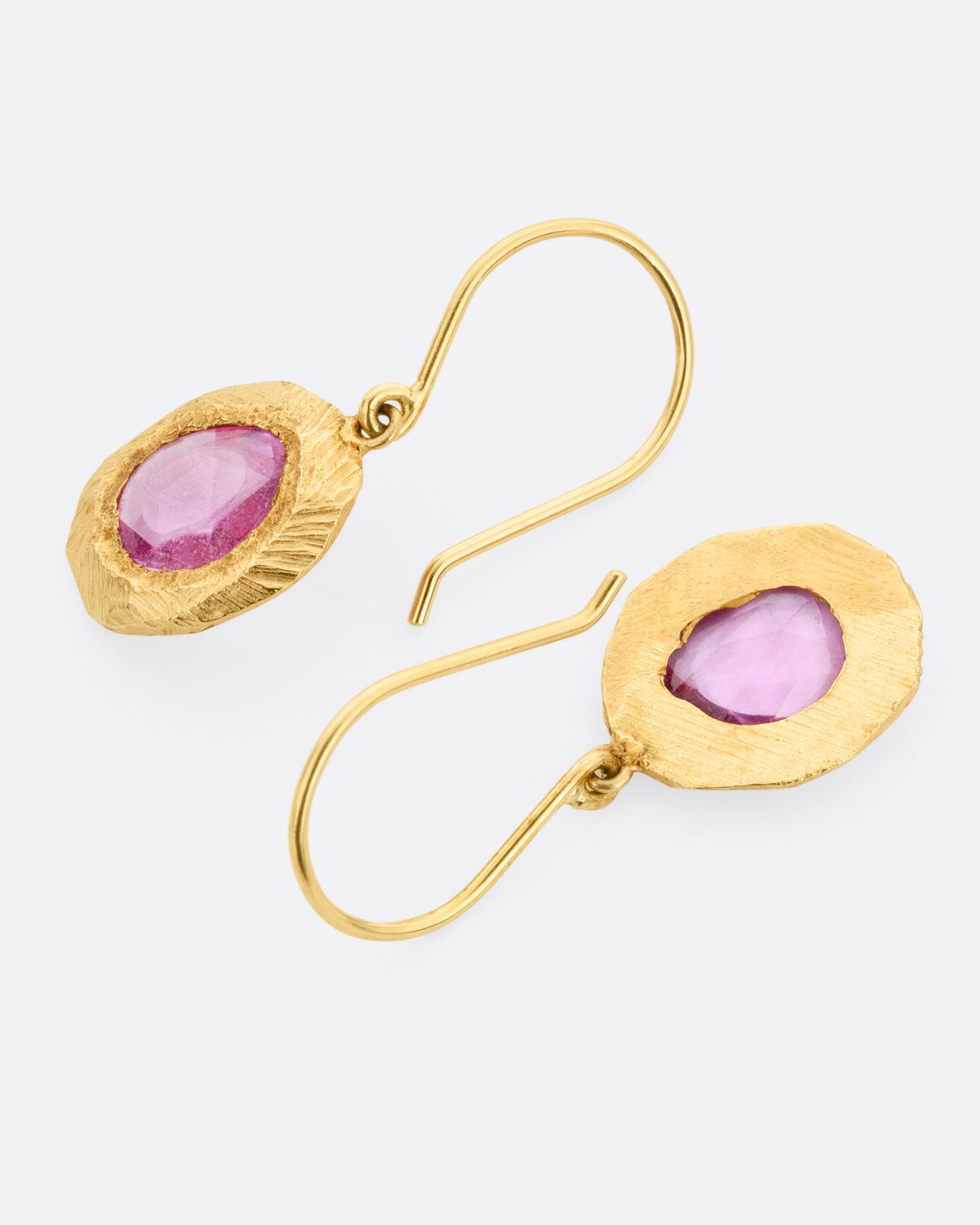 A pair of yellow gold drop earring with rose cut pink sapphires. Shown lying flat, one from the front, the other from the back.