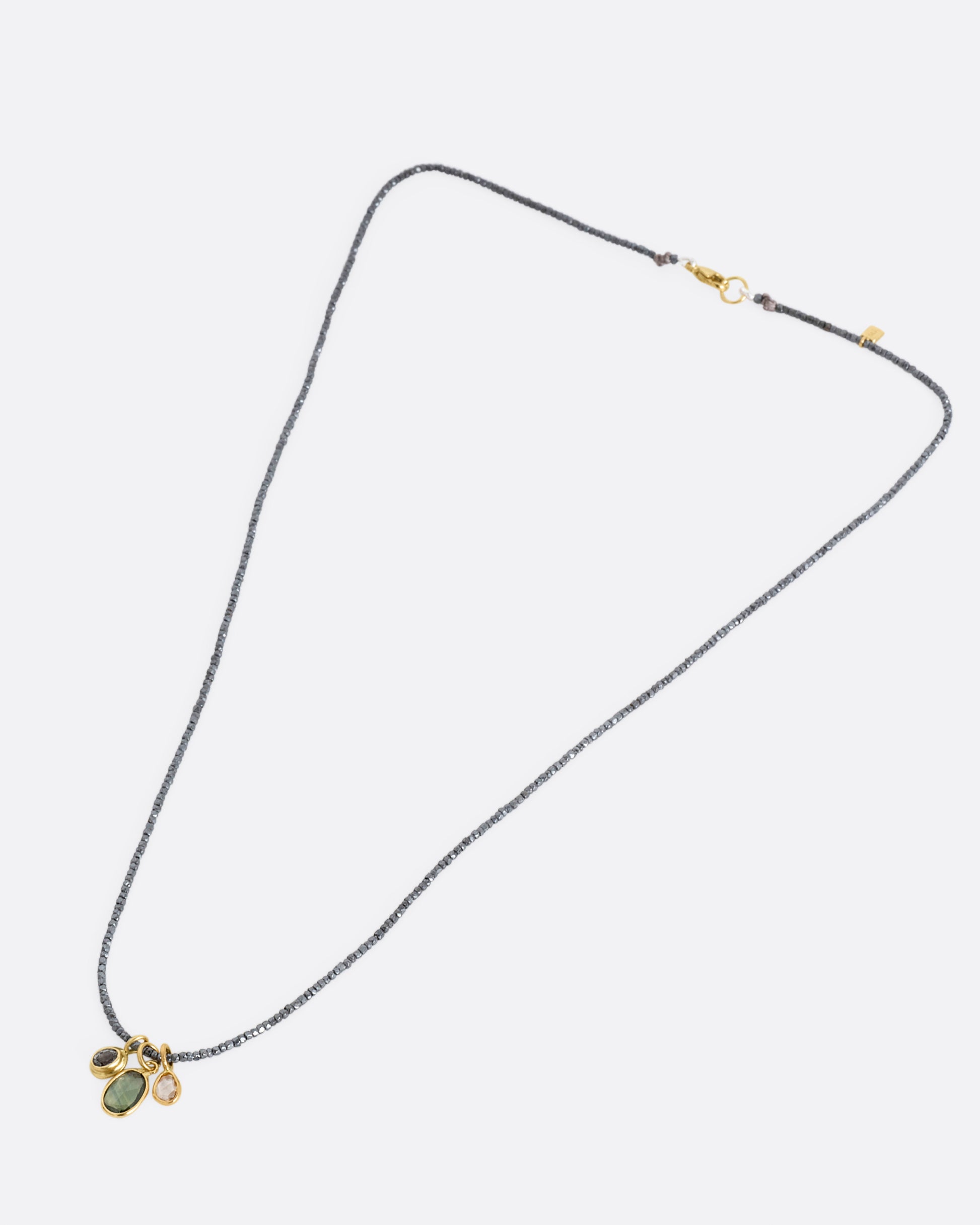 A necklace with silver beads and sapphire and diamond charms, shown lying flat from the front.