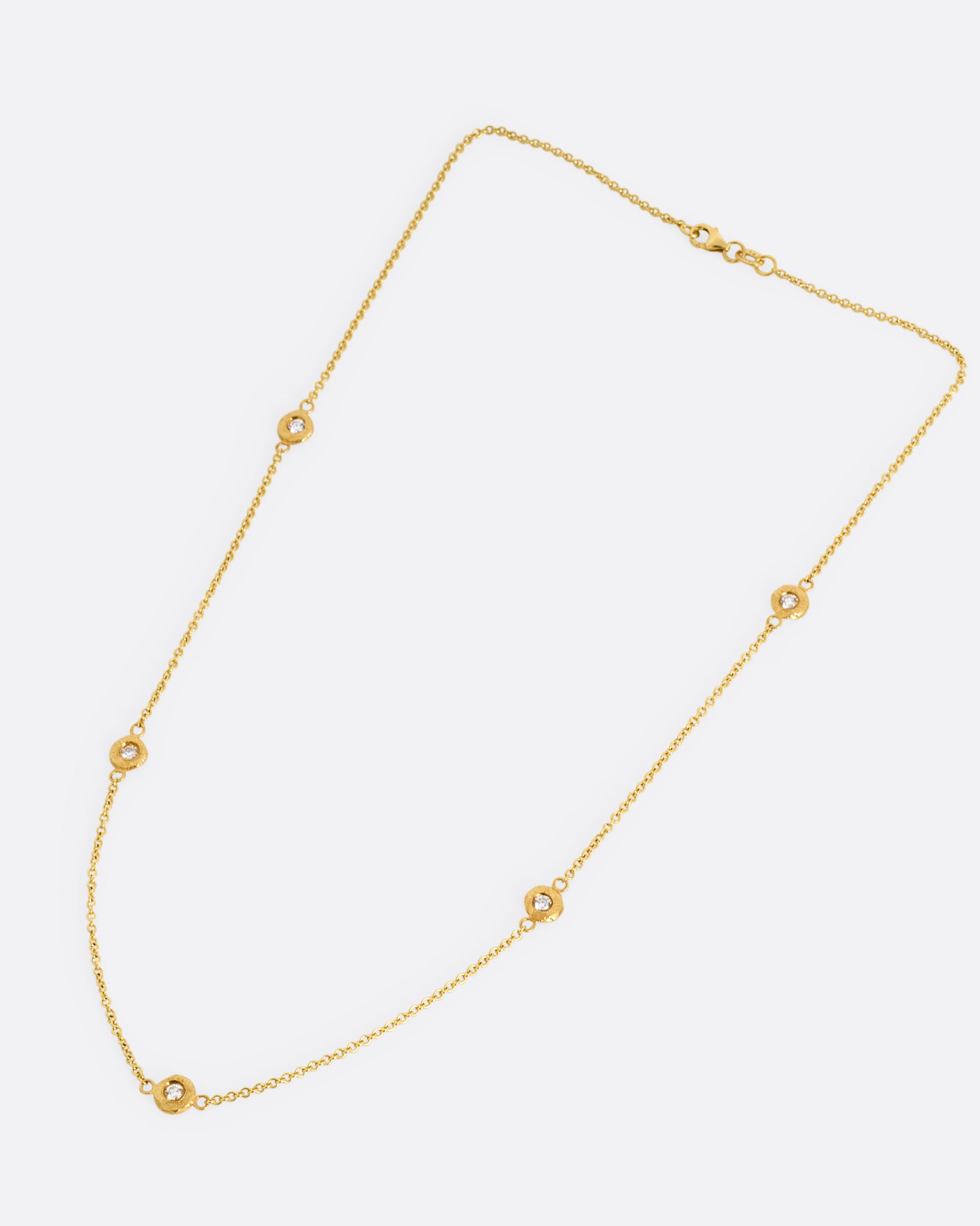 A yellow gold cable chain necklace with five diamonds set in hand carved bezels. Shown from the front. 