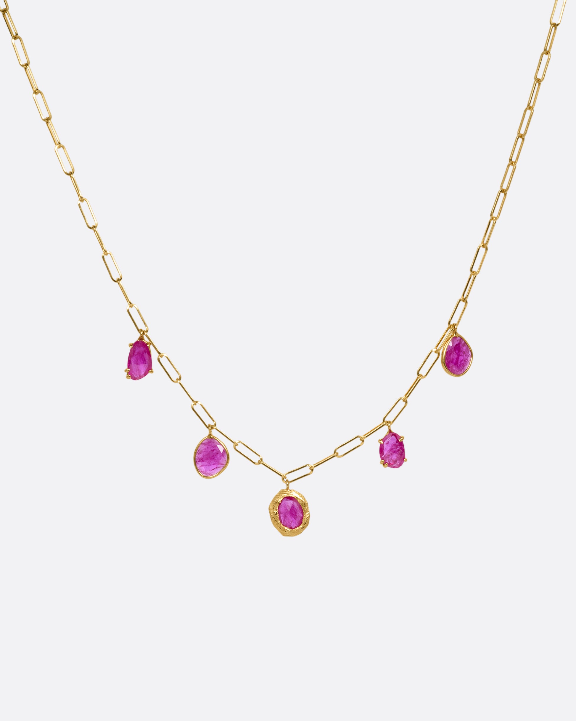 A yellow gold staple chain necklace with five rose cut ruby charms. Shown from the front.