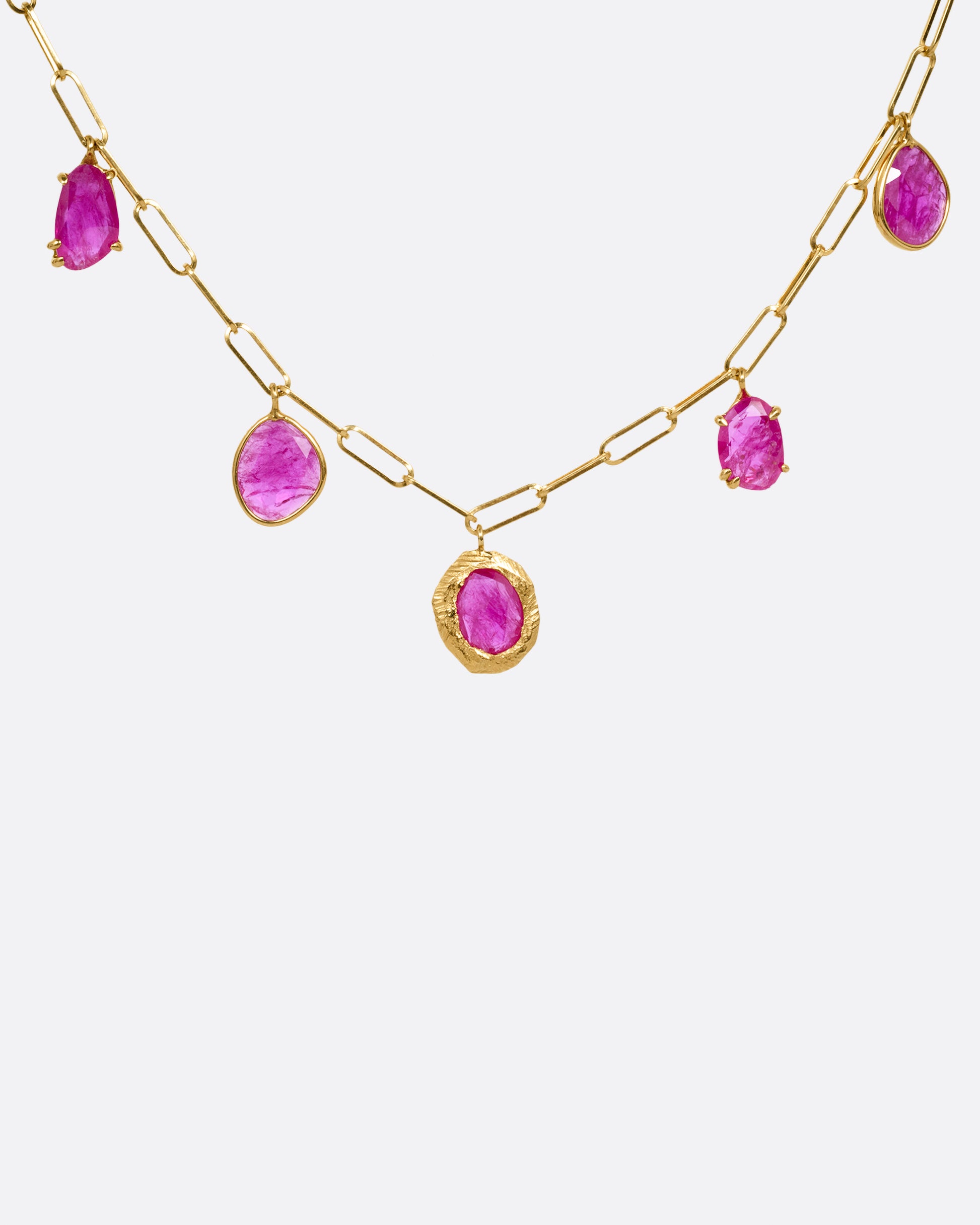 A yellow gold staple chain necklace with five rose cut ruby charms. Shown from the front.