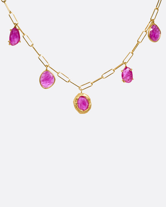 A yellow gold staple chain necklace with five rose cut ruby charms. Shown from the front.