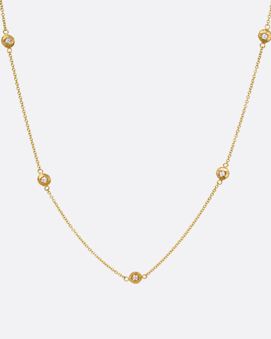 A yellow gold cable chain necklace with five diamonds set in hand carved bezels. Shown from the front. 