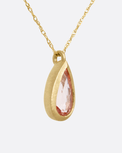 A yellow gold necklace with a bezel set teardrop shaped Imperial Topaz,shown from the side.