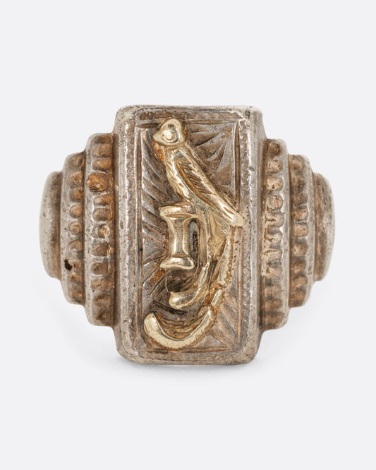 A sterling silver ring with stepped shoulders and a yellow gold bird. Shown from the front.