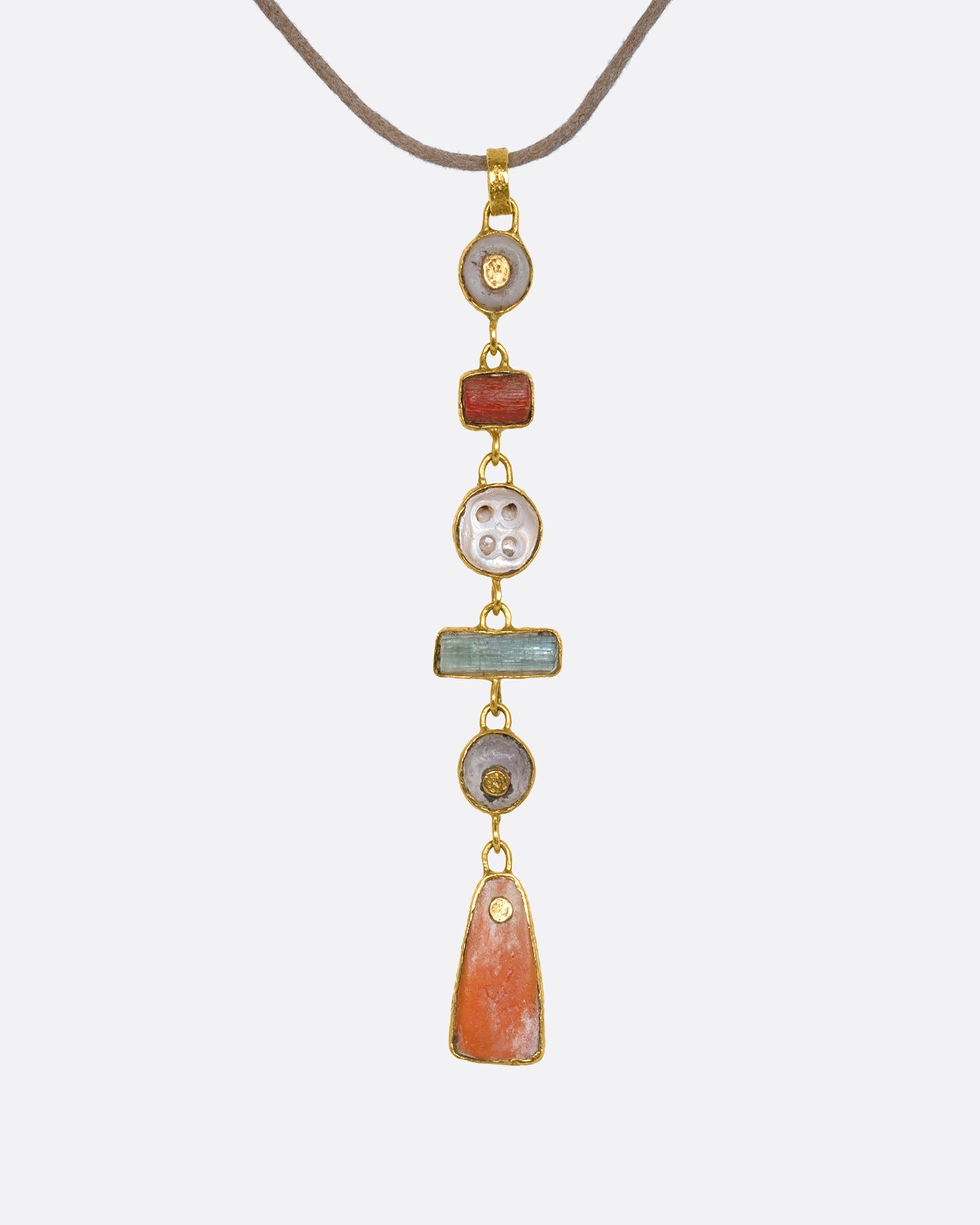 A tan cord necklace with six pre columbian elements hanging from it in a column, each wrapped in 22k gold. View from the front.