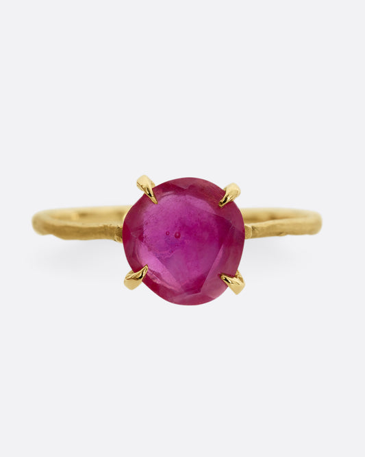 A yellow gold ring with a prong set ruby. Shown from the front.