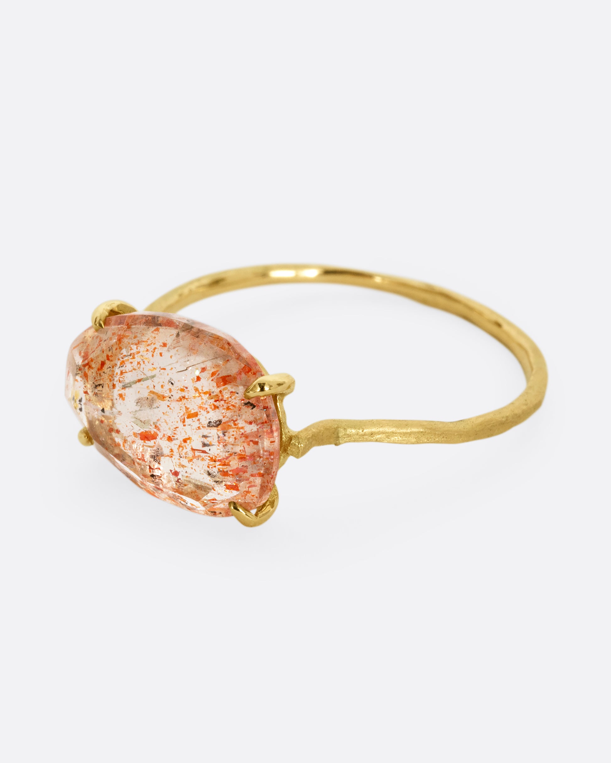 A yellow gold ring with a prong set sunstone. Shown from the side.