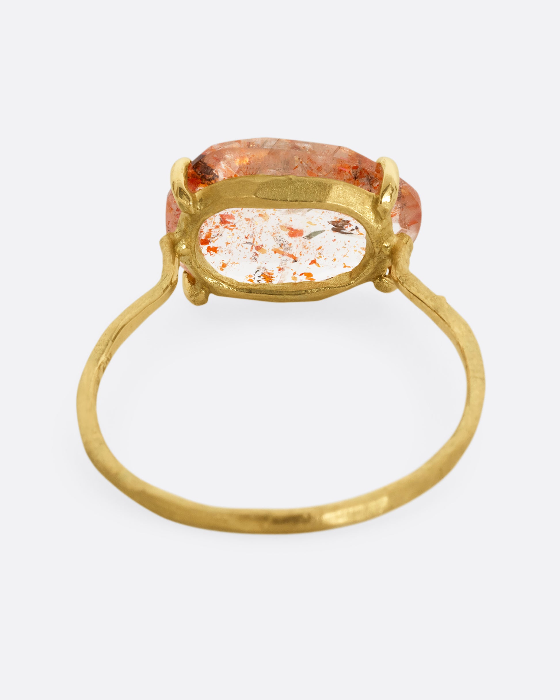 A yellow gold ring with a prong set sunstone. Shown from the back.