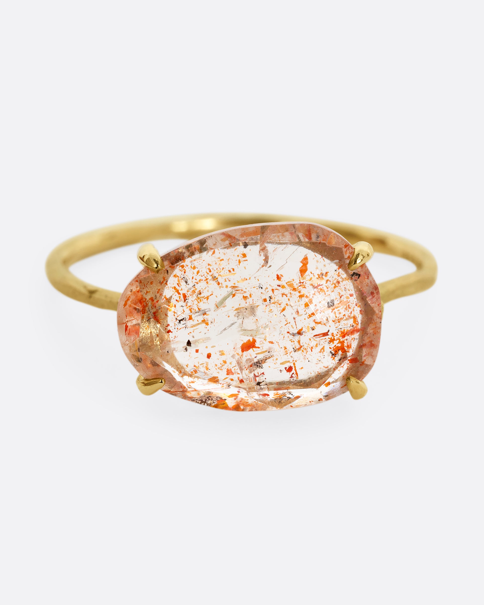 A yellow gold ring with a prong set sunstone. Shown from the front.