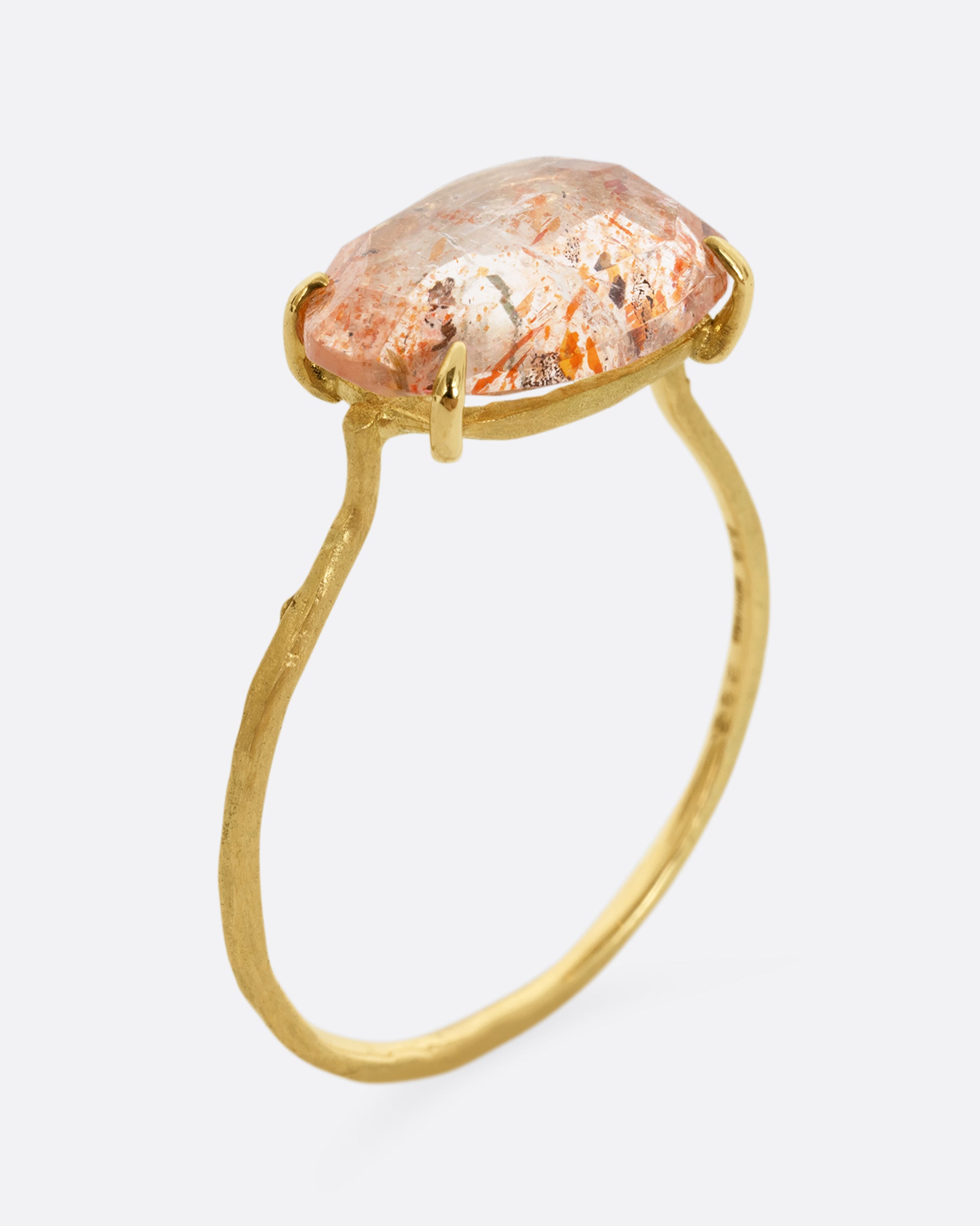 A yellow gold ring with a prong set sunstone. Shown standing up from the side.