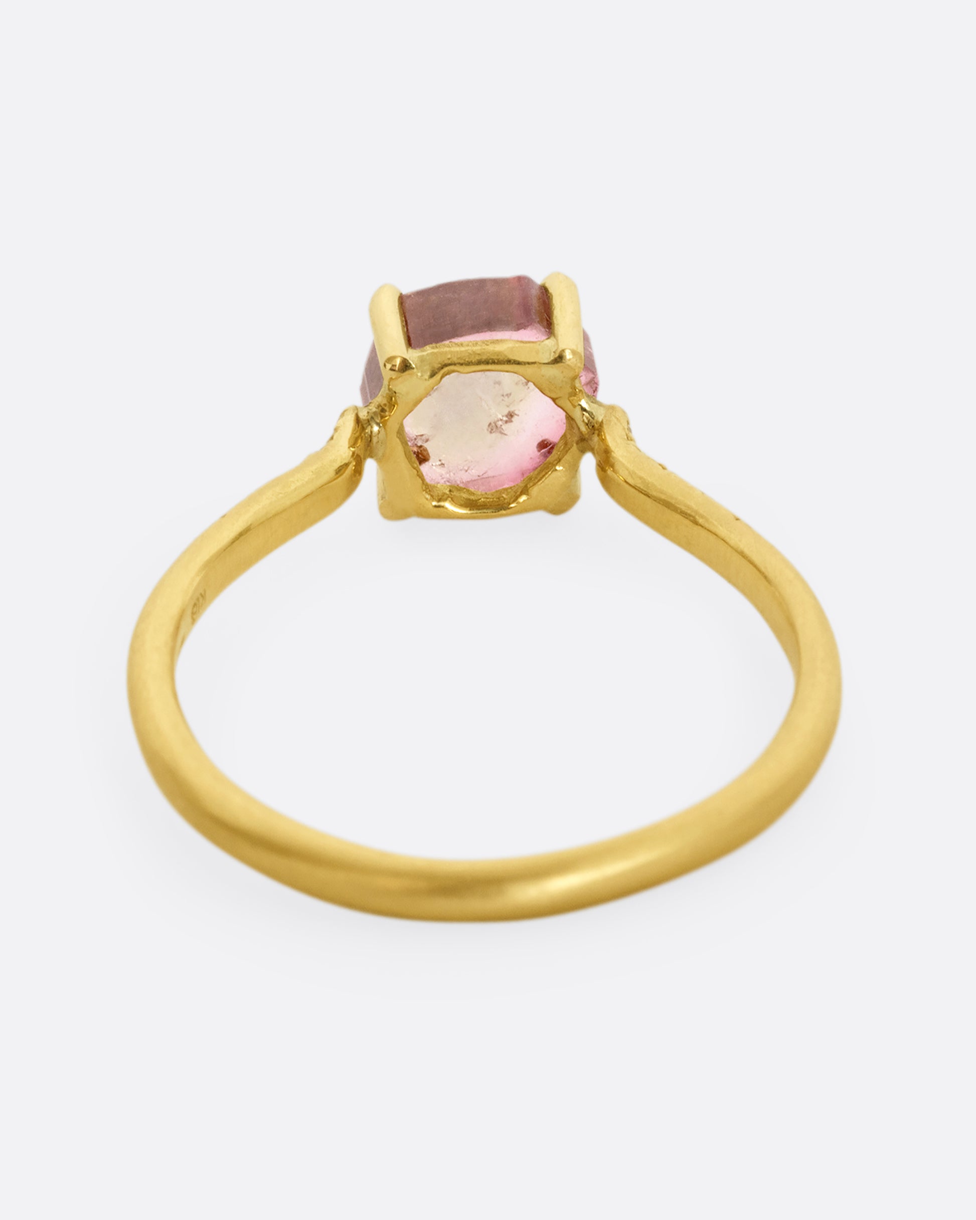 A yellow gold ring with a prong set pale pink bicolor tourmaline and four diamonds on either side of the band. Shown from the back.