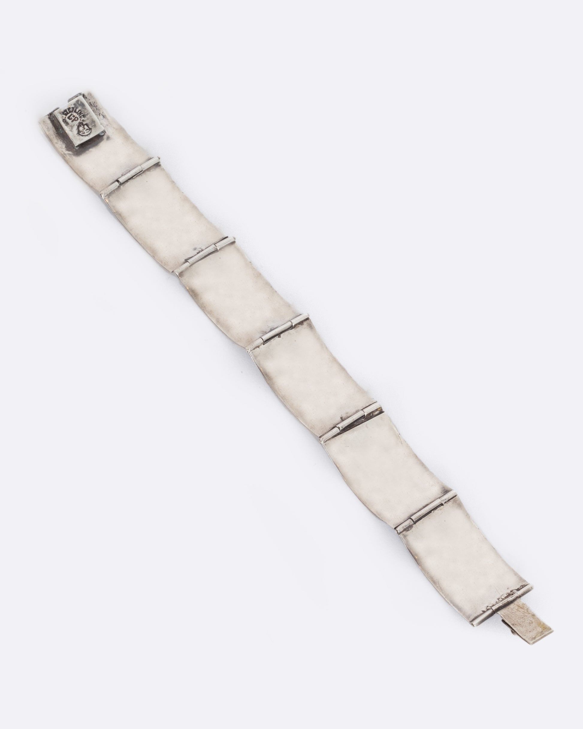 A sterling silver bracelet with rectangular links containing three abalone stations on each. View from the back, laying flat.