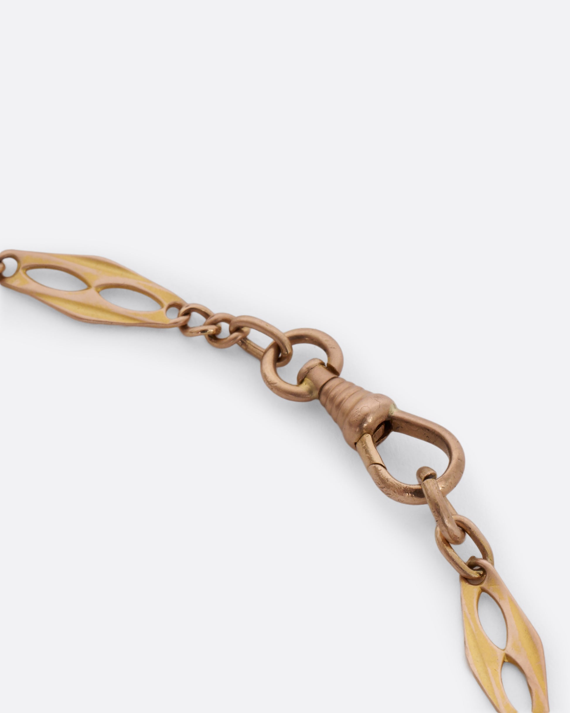 A yellow gold watch chain with fancy links. View of the dog clasp.