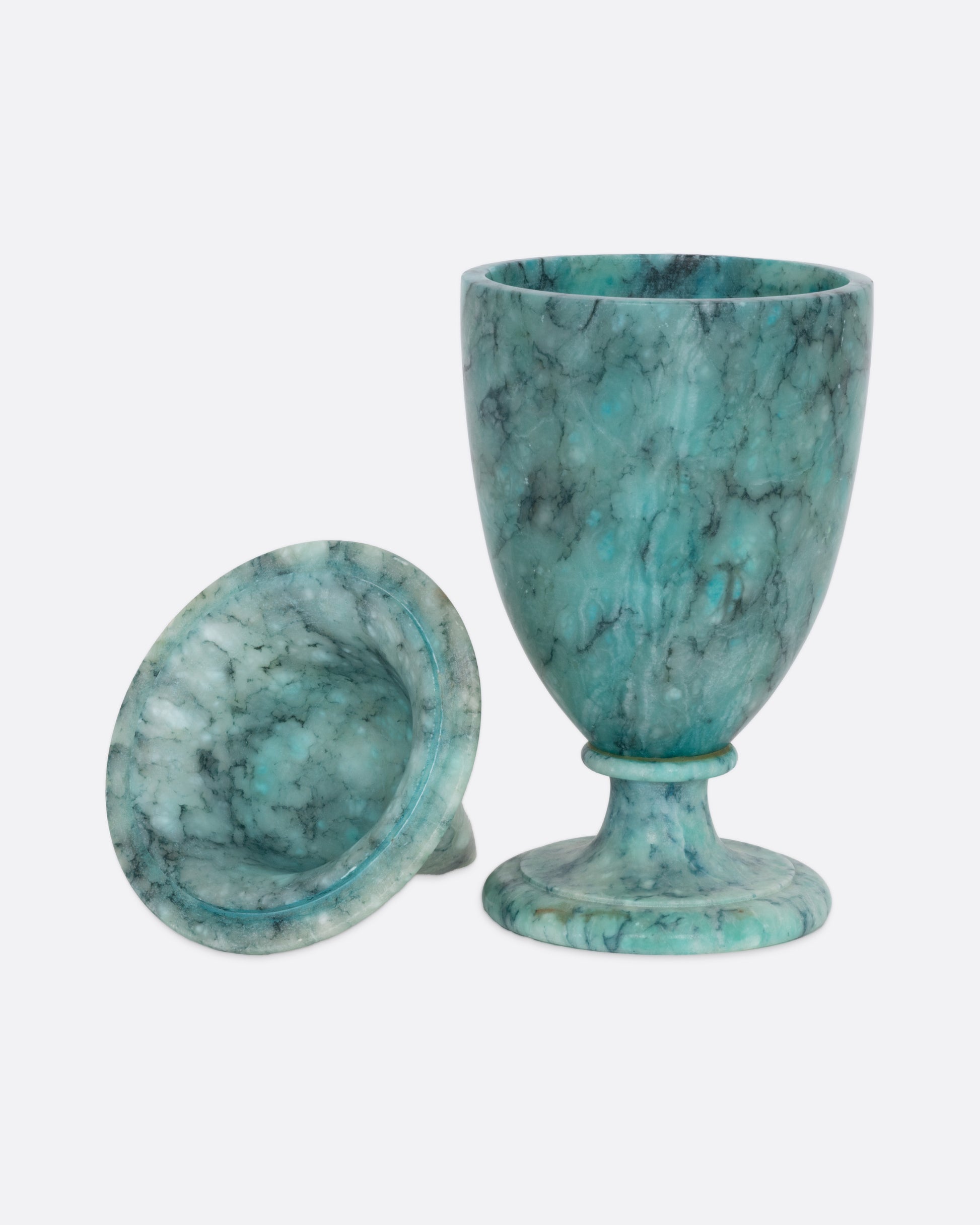 A turquoise colored ornate alabaster vessel with a lid, shown open with the lid on its side from the front.