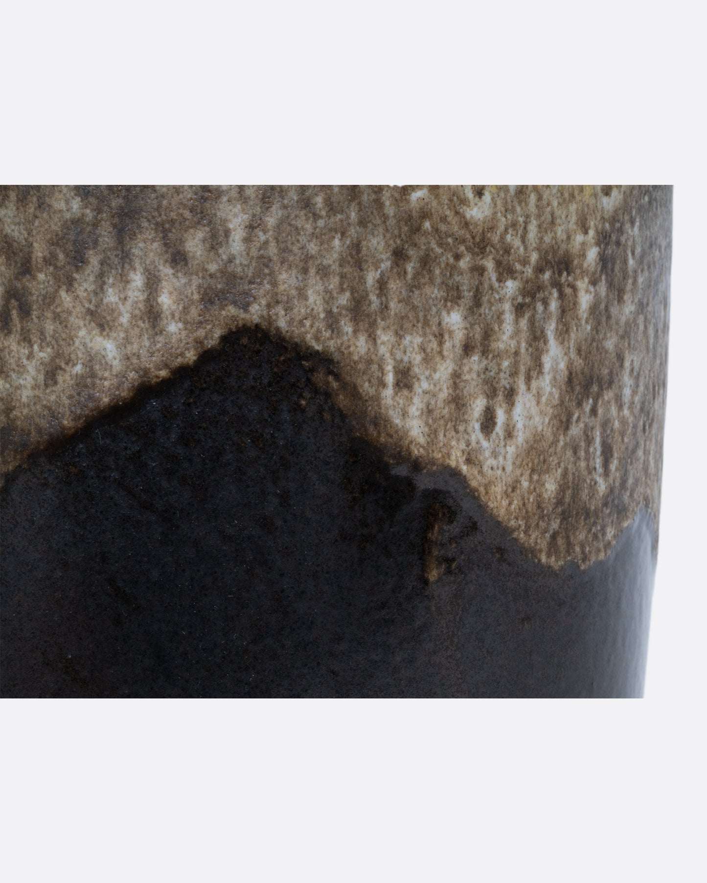 Close-up of a ceramic vase with a gradient from speckled tan to deep brown.