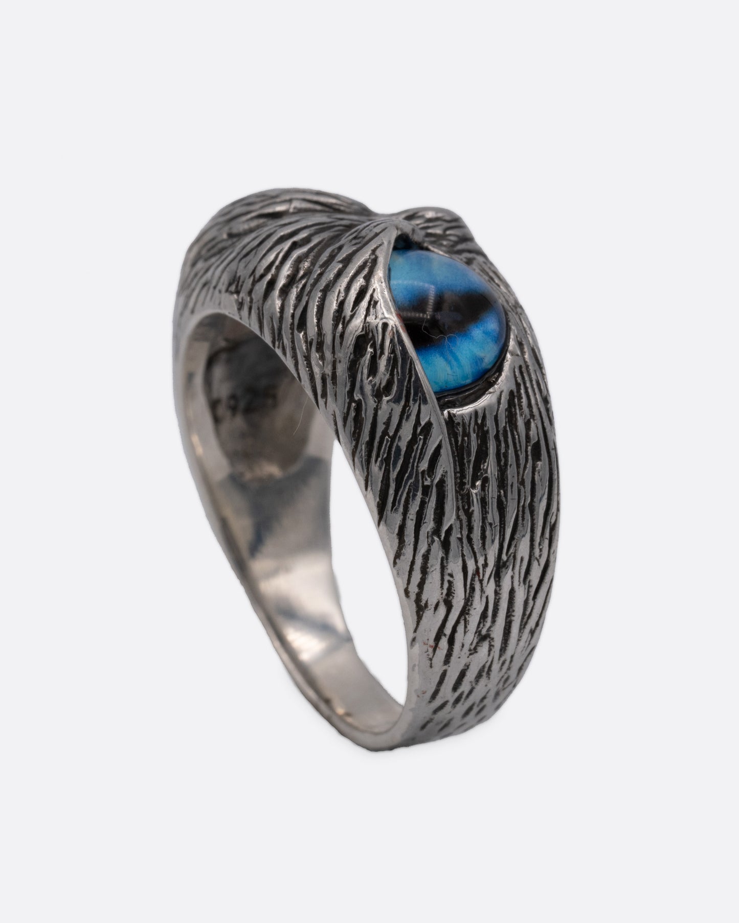 A silver ring with two blue glass eyes across the front. Shown from the side standing up.