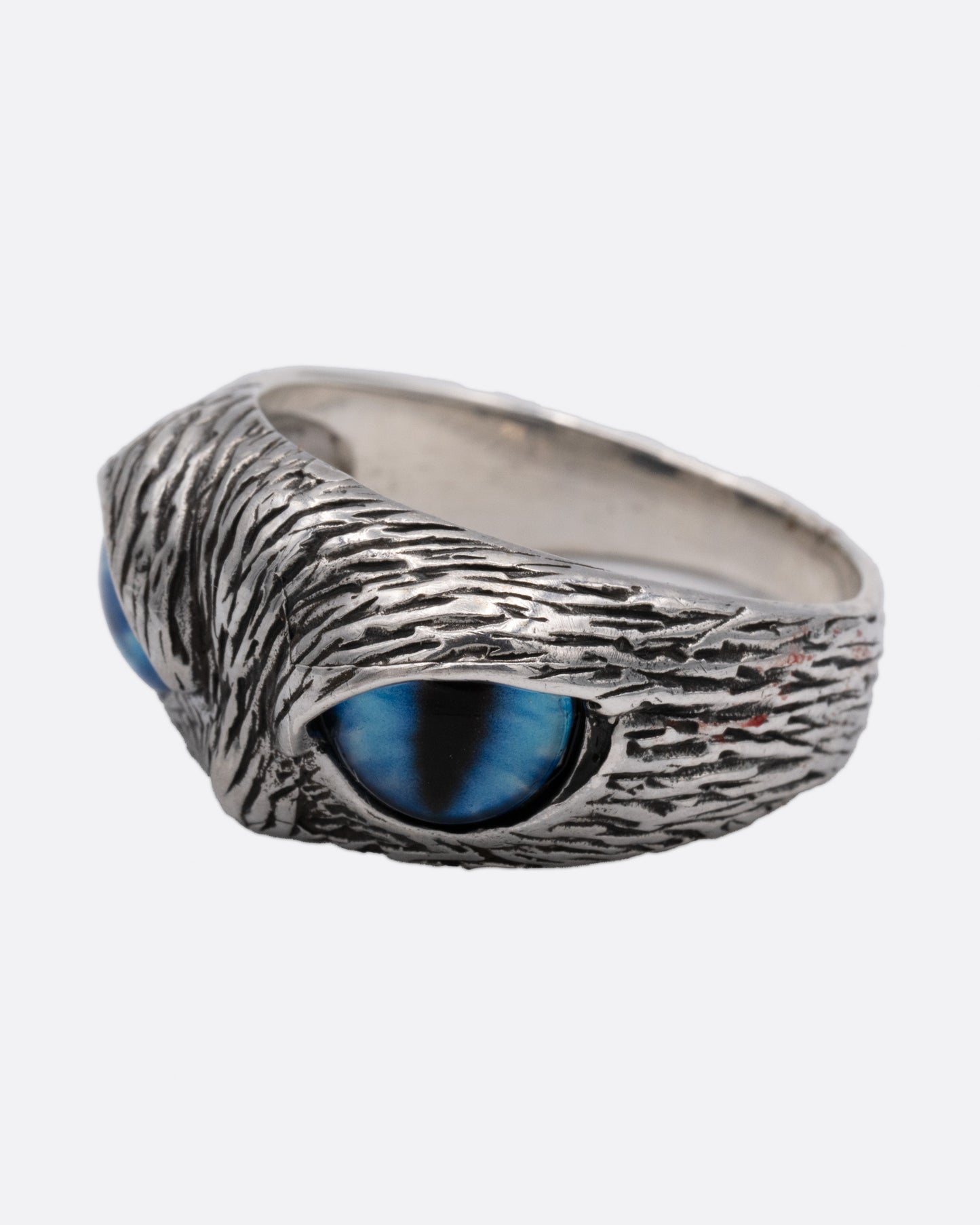 A silver ring with two blue glass eyes across the front. Shown from the side.