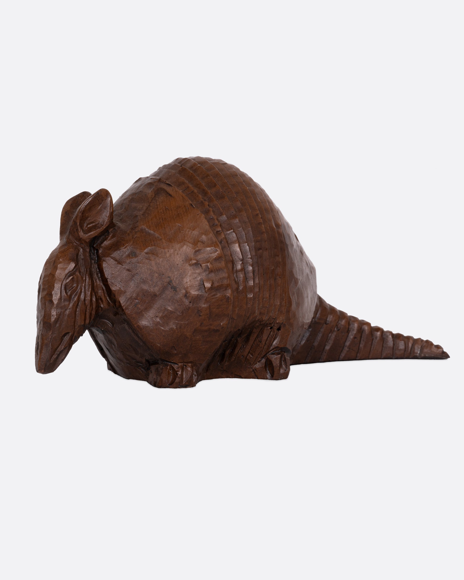 A wooden armadillo sculpture shown from the side.