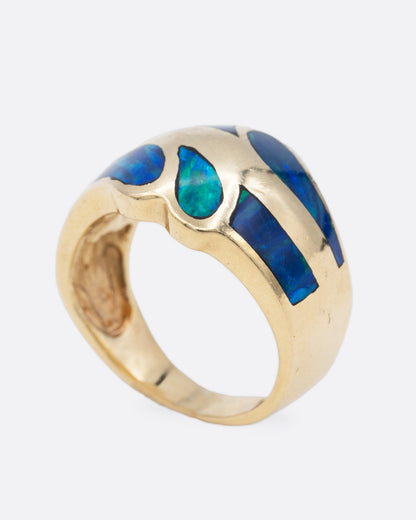 A yellow gold ring with an abstract inlay of opal. Shown from the side standing up.