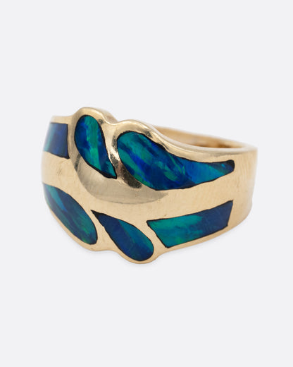 A yellow gold ring with an abstract inlay of opal. Shown from the side.