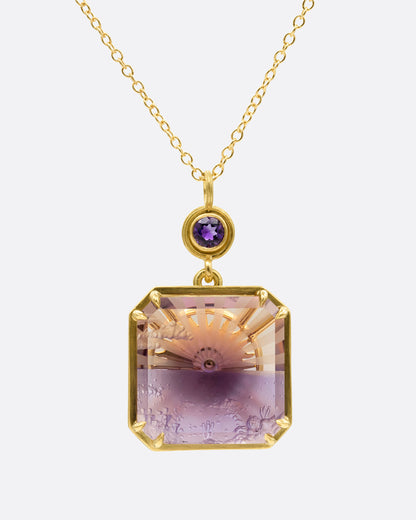 A yellow gold pendant necklace with an ametrine sunset carving with a gold sun face on its reverse. A round amethyst hovers just above this double sided pendant. Shown from the front.