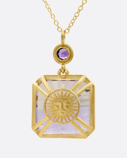 A yellow gold pendant necklace with an ametrine sunset carving with a gold sun face on its reverse. A round amethyst hovers just above this double sided pendant. Shown from the back.