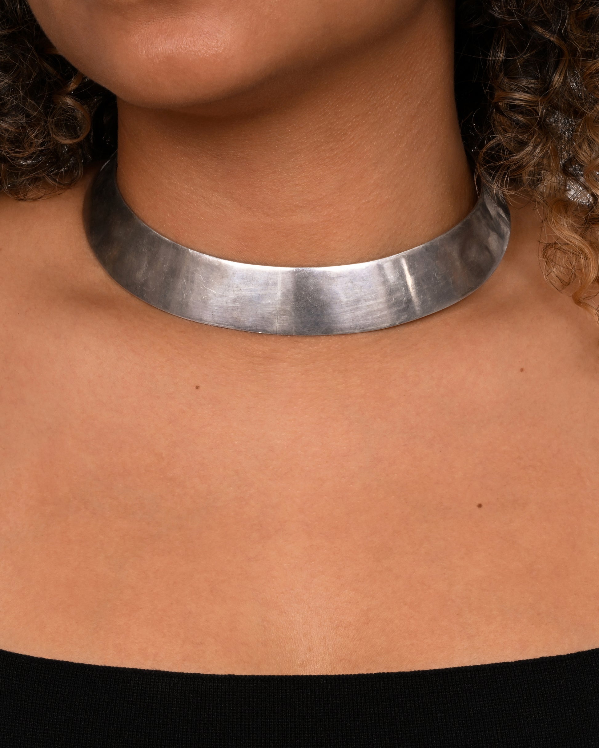 A flat sterling silver collar or choker. Shown on a neck.