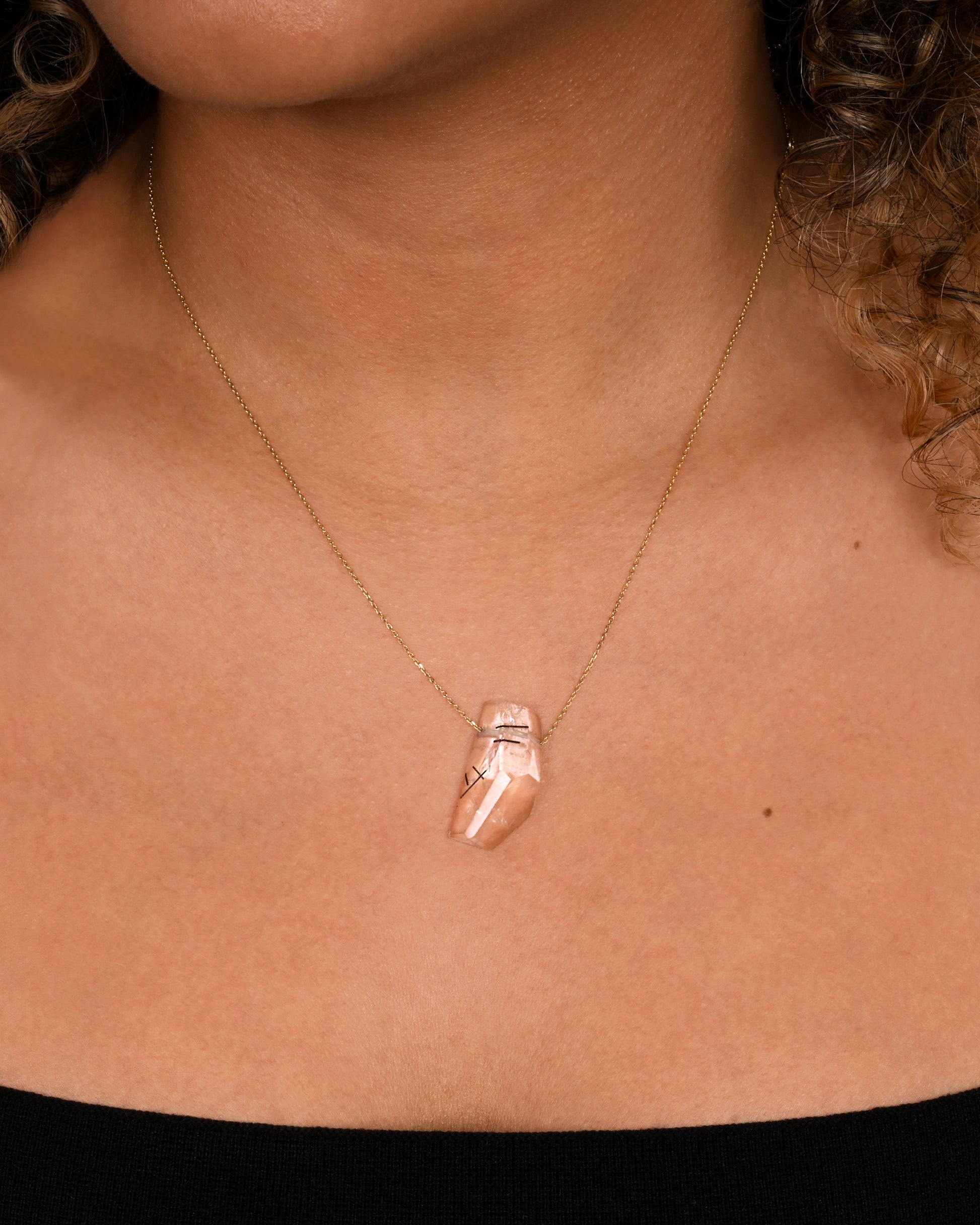 A drilled tourmalinated quartz on a fine yellow gold chain. Shown worn around the neck.