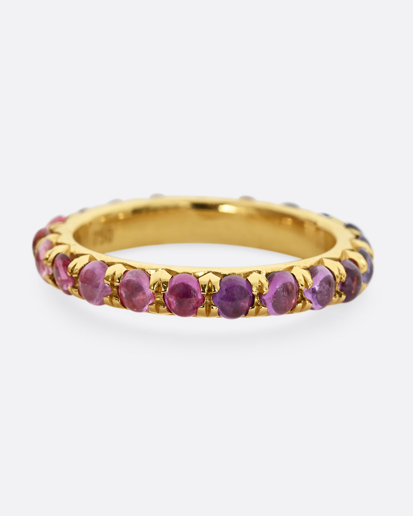 A yellow gold eternity band with pink and purple sapphire cabochons. 