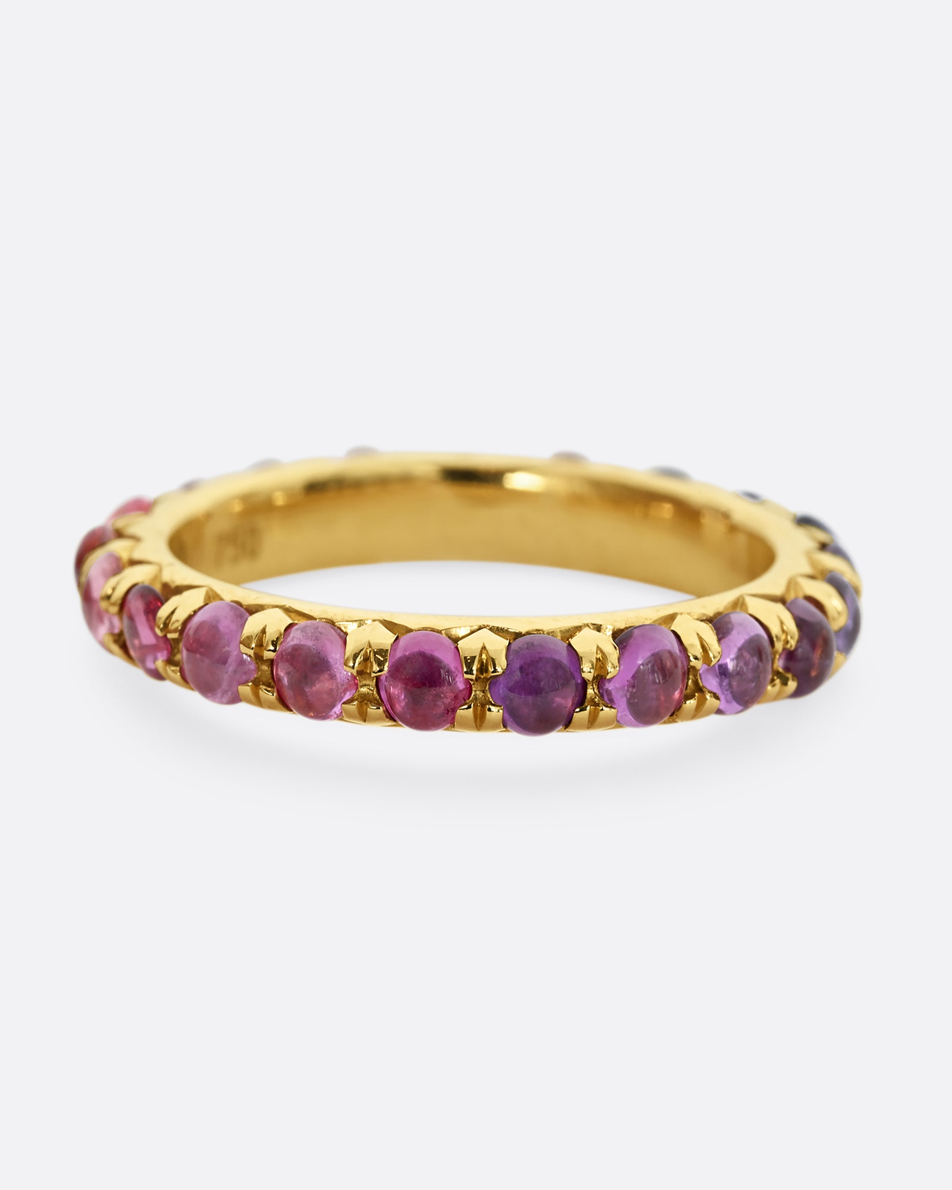 A yellow gold eternity band with pink and purple sapphire cabochons. 