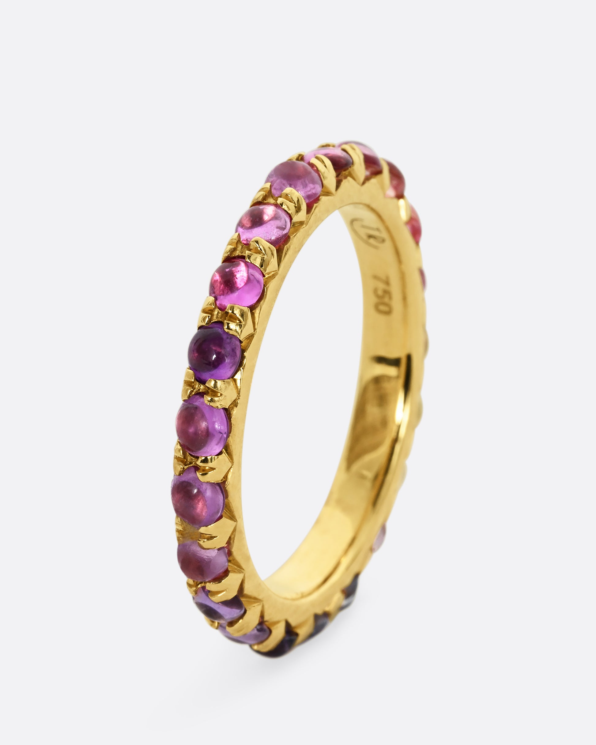 A yellow gold eternity band with pink and purple sapphire cabochons. Show from the side, standing up.