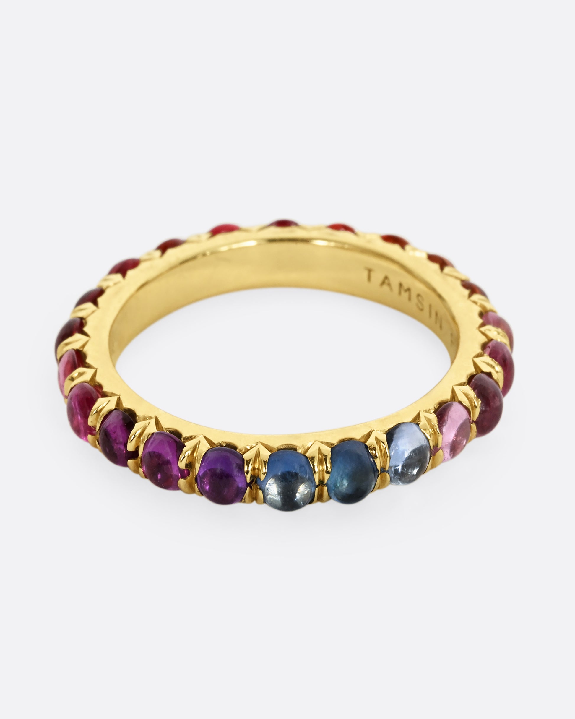 A yellow gold eternity band with rainbow sapphire cabochons.