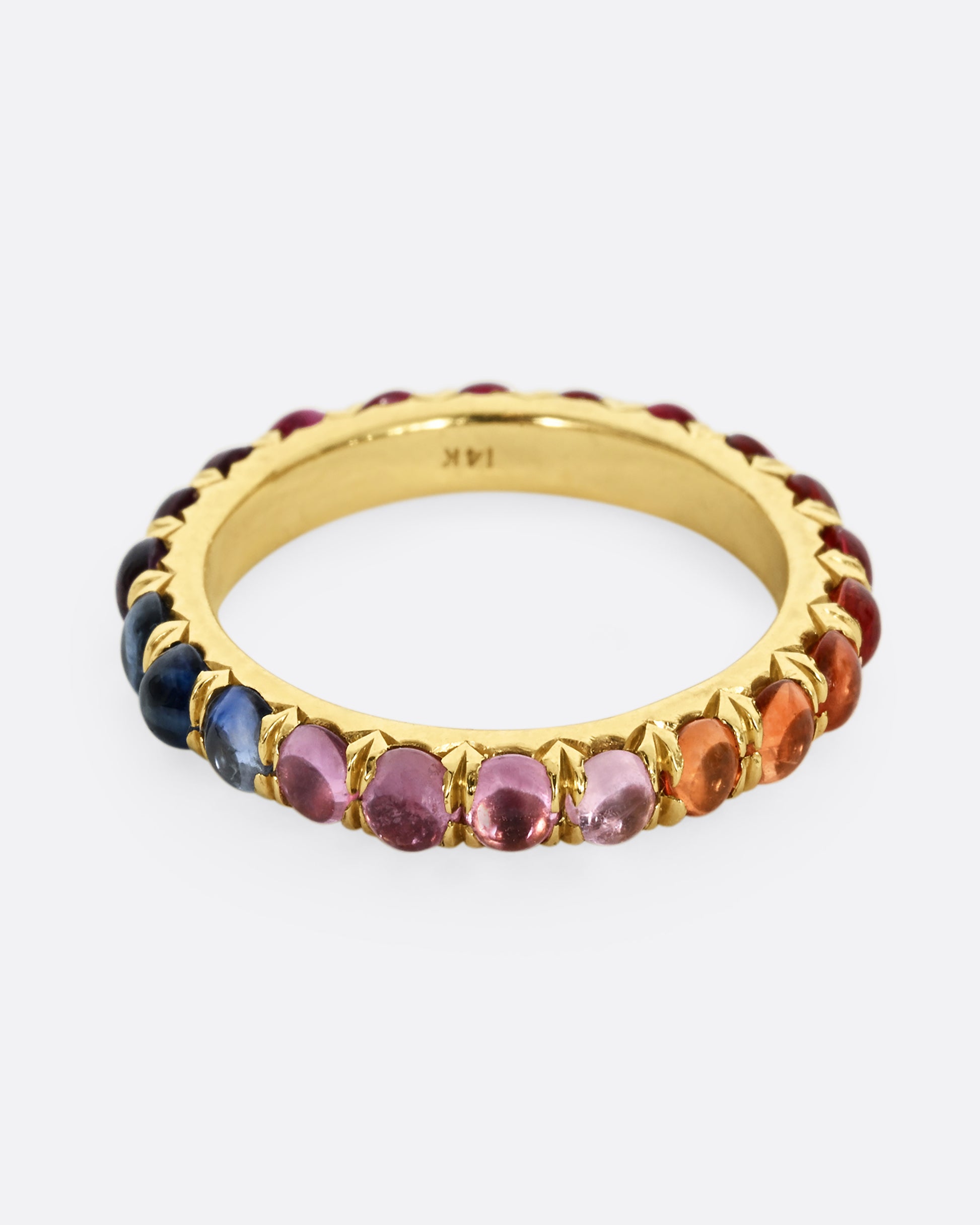 A yellow gold eternity band with rainbow sapphire cabochons.