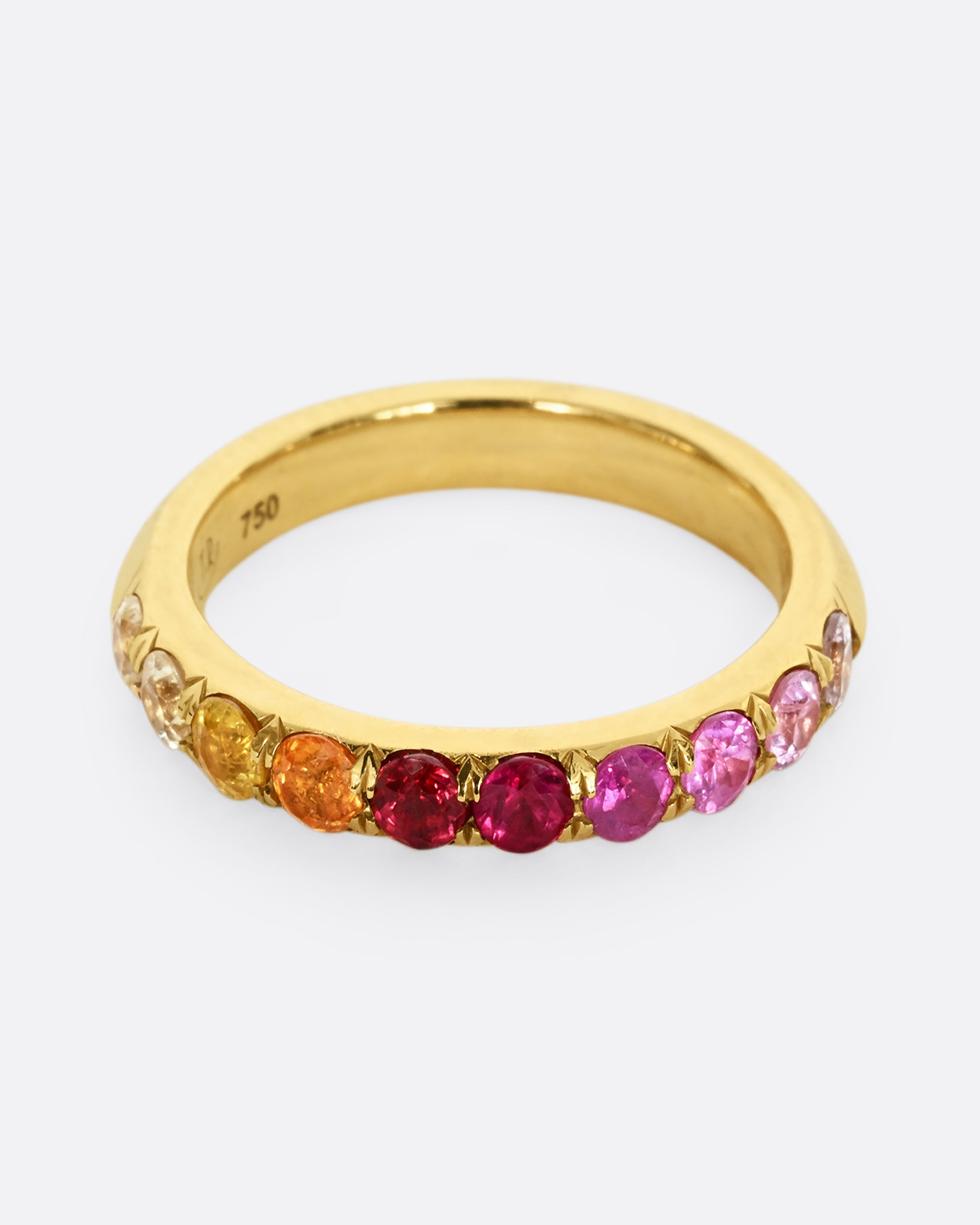 A yellow gold half eternity band with gradient orange red and pink cut sapphires. Shown from the front.